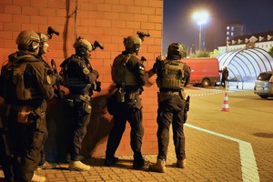 pięciu policjantów stoi przy ścianie budynku
