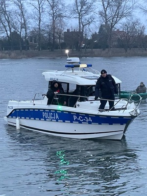 łódź policyjna pływająca po jeziorze z dwoma policjantami na pokładzie