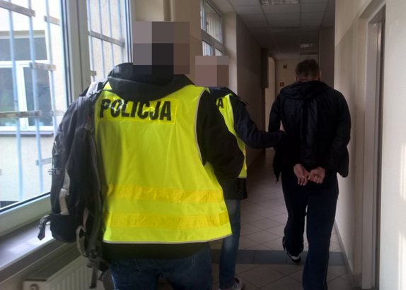 Policjanci prowadzą zatrzymanego mężczyznę