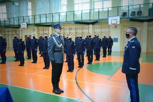 sala gimnastyczna Oddziału Prewencji Policji w Łodzi, uroczystość ślubowania policjantów, dowódca uroczystości składa meldunek komendantowi wojewódzkiemu, w tle stojący pododdział policjantów