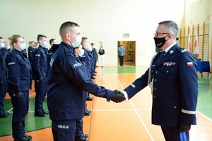sala gimnastyczna OPP w Łodzi. uroczystość ślubowania policjantów. komendant ściska dłoń nowo przyjętemu policjantowi