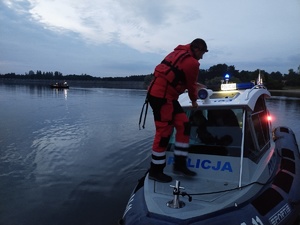 łódż motorowa na wodzie, wieczór, na niej ratownicy i policjanci