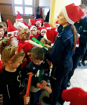 policjantka w czapce Mikołaja rozdaje dzieciom odblaski