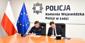Komendant Wojewódzki Policji w Łodzi oraz Prezydent Miasta Skierniewice siedzą za stołem podpisują porozumienie.