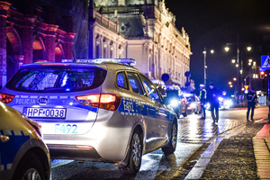 Radiowóz, policjanci stojący na ulicy.