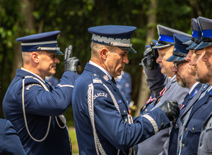 Zastępca Komendanta Głównego przypina medal policjantowi, za nim stoi Komendant Wojewódzki Policji w Łodzi i oddaje honor.