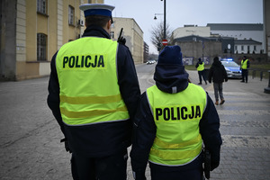 Policjanci w kamizelkach odblaskowych z napisem policja.