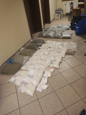 Na podłodze ułożone torebki foliowe z suszem roślinnym i białym proszkiem.