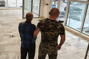 Policjant prowadzi zatrzymanego.