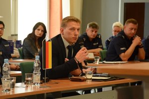 uczestnicy konferencji przy stołach podczas wystąpienia