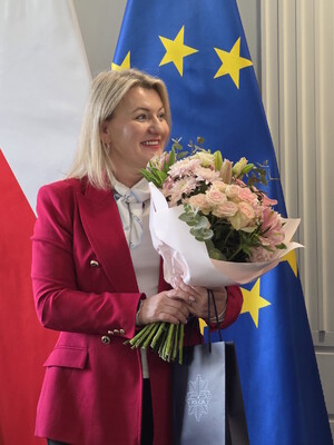 mł. insp. Hanna Kowalewicz, Pełnomocniczka Komendanta Wojewódzkiego Policji w Gdańsku ds. Ochrony Praw Człowieka pełniąca funkcję Zastępczyni Przewodniczącej Zespołu stoi z kwiatami za pracę na rzecz Zespołu na tle flag Polski i Unii Europejskiej.