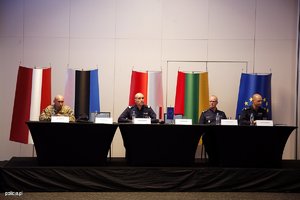 Zdjęcie przedstawia przedstawicieli Policji i służb siedzących przy trzech złączonych ze sobą stołach okrytych czarnym suknem. Wśród osób siedzących znajduje się Zastępca Komendanta Głównego Policji - nadinsp. Roman Kuster.

 w tle widać flagi Polski oraz partnerów projektu: Łotwy, Estonii, Litwy oraz flagę Unii Europejskiej.