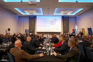 Zdjęcie przedstawia uczestników konferencji widzianych od tyłu i patrzących na znajdujący się w centralnej części sali ekran, na którym wyświetlana jest prezentacja dotycząca działań podejmowanych w ramach projektu.