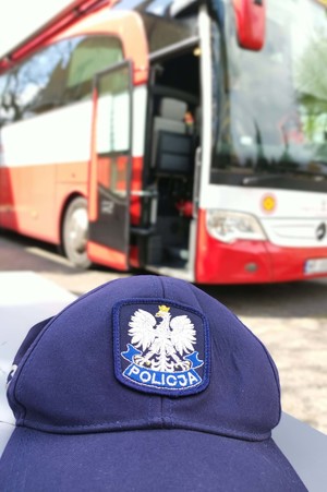 Policyjna czapka, w tle autobus do oddawania krwi