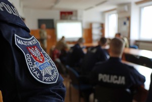 Umundurowani policjanci siedzący w sali wykładowej