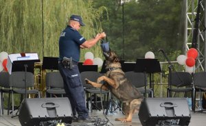 Umundurowany policjant stojąca na scenie z psem służbowym