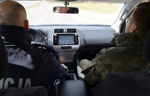 Policjant i żołnierz jadący radiowozem