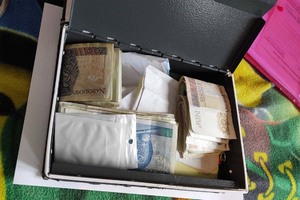 Wnętrze skrytki wypełnione plikami banknotów o nominale 200 i 50 PLN oraz foliowymi torebkami strunowymi.