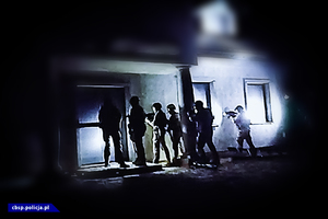 policjanci w ciemnym miejscu szykują się do wejścia do nieruchomości