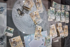 Banknoty o nominałach 100 oraz 200 PLN leżące na blacie stołu.