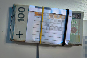 Plik banknotów o nominale 100 PLN spięty gumką.
