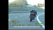 Stopklatka z policyjnego wideorejestratora. Motocyklista na zakręcie w prawo, widoczny od tyłu, jadący z prędkością 182,3 km/h