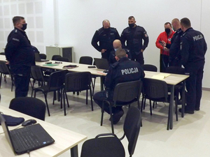 Uczestnicy szkolenia - policjanci i ratownicy STORAT na auli Oddziału Prewencji Policji w Rzeszowie. Policjanci i ratownik STORAT stoją wokół stolika, dwóch siedzi przy nim.