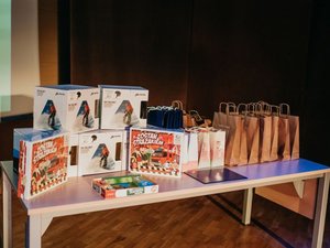 Kolorowa fotografia. Na stoliku poukładane nagrody dla zwycięzców konkursu. Kaski narciarskie i torebki papierowe z nagrodami rzeczowymi w środku.