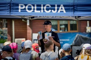 Policjanci podczas spotkania z dziećmi w Polańczyku. Na zdjęciu policjant wydziału prewencji przy stoisku profilaktycznym z dziećmi