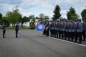 Po lewej policjant z szablą, w środku Komendant Wojewódzki Policji w Rzeszowie wita się ze sztandarem. Po prawej poczet sztandarowy i kompania honorowa.