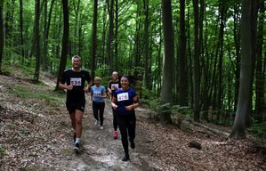 Grupa osób biegnie lasem