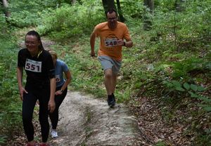 Dwie kobiety i mężczyzna biegną lasem