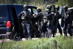 Policyjni antyterroryści i amerykańscy żołnierze podczas wspólnych ćwiczeń, na terenie zielonym.
