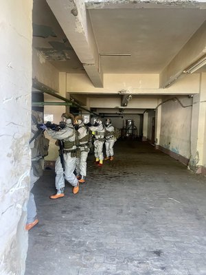 umundurowani policyjni kontrterroryści  w szyku bojowym, z bronią wchodzą do budynku