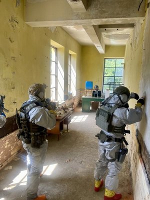 umundurowani policyjni kontrterroryści  w szyku bojowym, z bronią sprawdzają pomieszczenia wewnątrz budynku