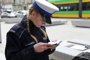 policjantka ruchu drogowego w białej czapce czyta notatnik służbowy