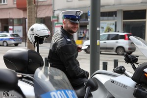policjant ruchu drogowego siedzi na policyjnym motocyklu i się uśmiecha