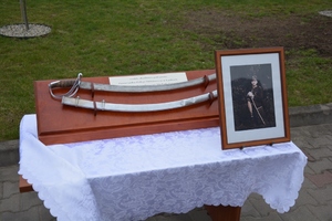 Pamiątkowa szabla na stoliku, obok zdjęcie jednego z pomordowanych policjantów