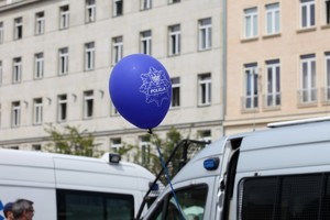 Niebieski balon z napisem Policja na tle radiowozów oznakowanych