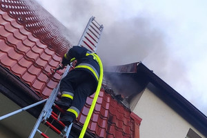 Strażak podczas akcji wchodzący po drabinie na dach