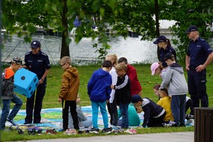 Dzieci w trakcie gry w plenerową grę planszową. Duża plansza rozłożona na trawniku i dzieci na niej