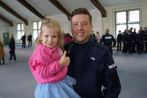 Ślubujący policjant z córeczką na rękach