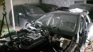 Fotografia kolorowa. Przedstawia wnętrze garażu, a w nim trzy odzyskane samochody.  Jeden z pojazdów jest częściowo rozmontowany.