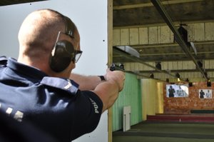 Policjant oddaje strzeł w kierunku tarczy podczas konkurencji z umiejętności strzeleckich