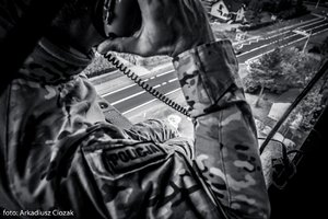 Zdjęcie czarno-białe. Uczestnik szkolenia oraz widok z wnętrza śmigłowca