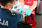 Pielęgniarka nakleja plaster na ręce umundurowanej policjantce