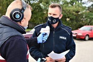 umundurowany policjant udziela informacji dla dziennikarza z Radia Express, który trzyma w dłoni mikrofon.