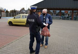 Umundurowana policjantka wręcza mężczyźnie odblaskową torbę.