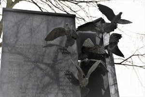 Pomnik upamiętniający ofiary tragedii. Na zdjęciu jego górna część z imionami i nazwiskami zmarłych oraz symbolicznymi gołębiami, nawiązującymi do wydarzeń.