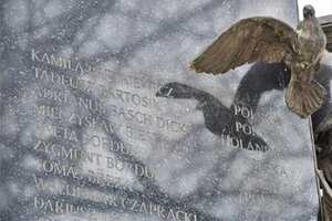 Pomnik upamiętniający zmarłe osoby. Widoczny symboliczny gołąb oraz nazwiska zmarłych.